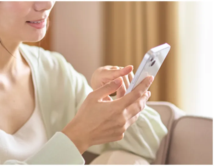 部屋でスマホを操作する女性